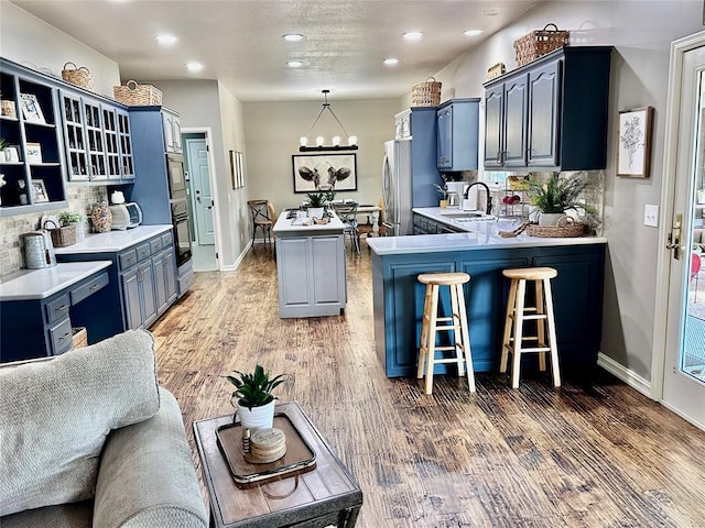 kitchen with sink, stainless steel appliances, dark wood-type flooring, kitchen peninsula, and decorative backsplash