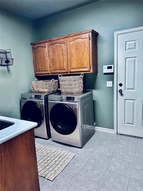 laundry area with cabinets, light tile patterned floors, and washer and clothes dryer