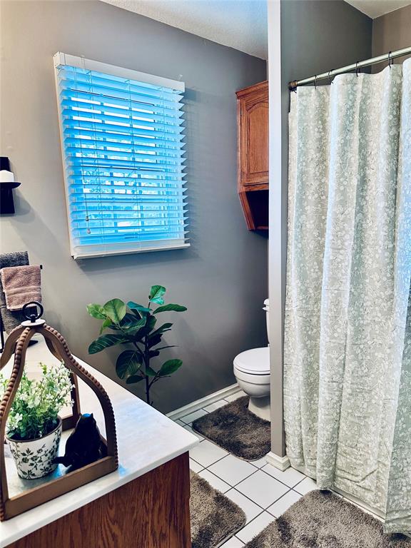 bathroom with tile patterned flooring, a shower with curtain, and toilet