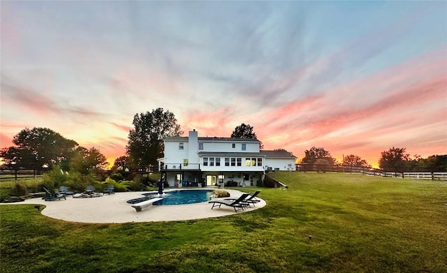 back house at dusk with a yard, a balcony, and a patio