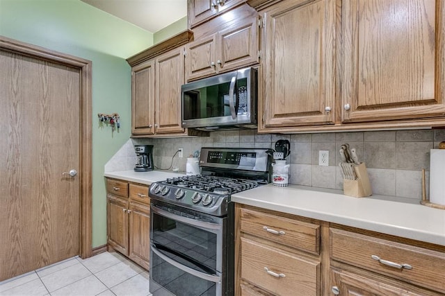 kitchen with appliances with stainless steel finishes, tasteful backsplash, and light tile patterned flooring