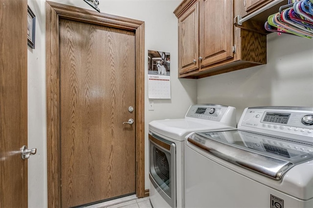 laundry area with cabinets, light tile patterned floors, and washing machine and clothes dryer