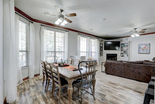 dining room featuring ceiling fan, light hardwood / wood-style floors, ornamental molding, and a textured ceiling