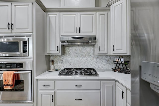 kitchen featuring light stone countertops, white cabinetry, backsplash, and appliances with stainless steel finishes