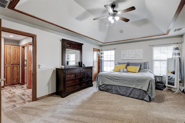 carpeted bedroom with a tray ceiling, multiple windows, and ceiling fan