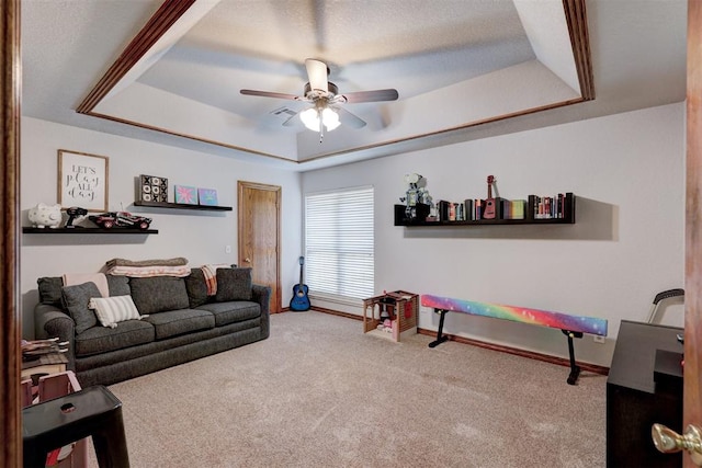 carpeted living room with a raised ceiling and ceiling fan