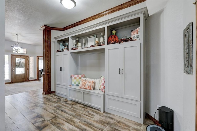 mudroom with a notable chandelier, a textured ceiling, and light hardwood / wood-style flooring