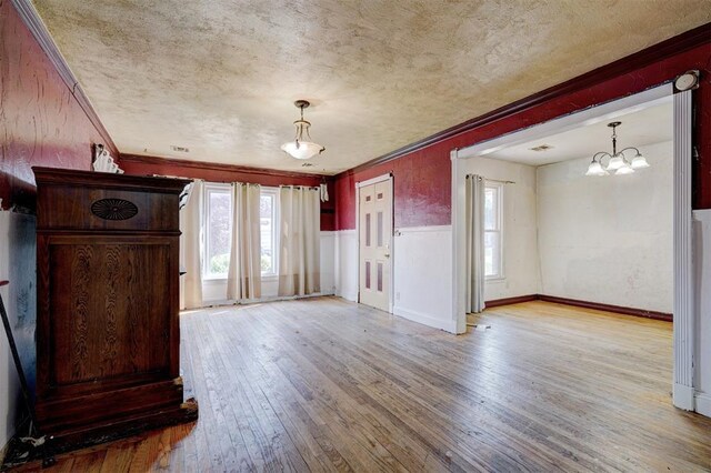 1413 Reding Dr, Oklahoma City, OK 73119 - unfurnished living room featuring light wood finished floors, plenty of natural light, a chandelier, ornamental molding, and a textured ceiling