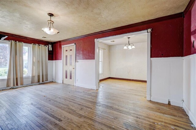 1413 Reding Dr, Oklahoma City, OK 73119 - empty room with light wood finished floors, ornamental molding, a chandelier, wainscoting, and a textured ceiling