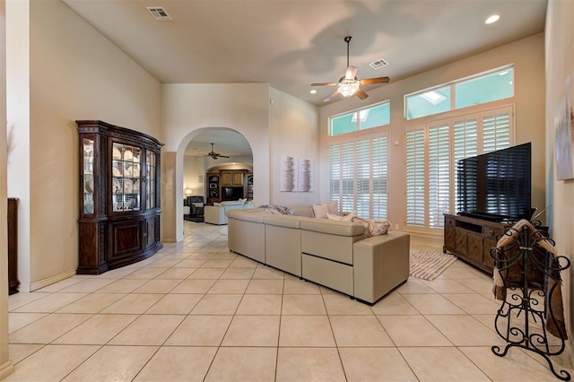 tiled living room with ceiling fan and a towering ceiling