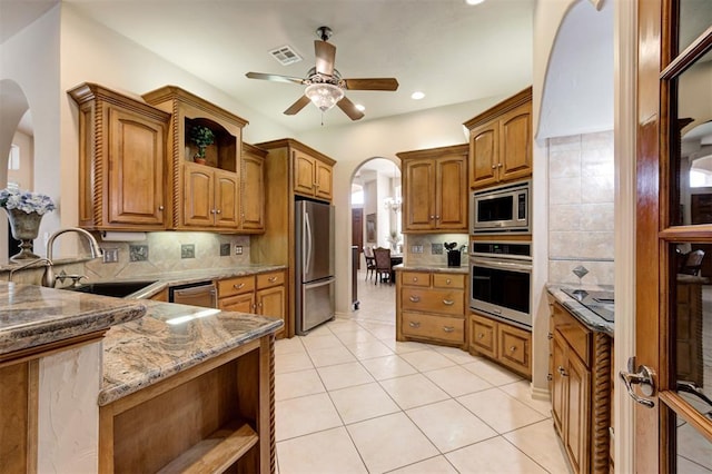 kitchen with sink, tasteful backsplash, stone countertops, light tile patterned flooring, and stainless steel appliances