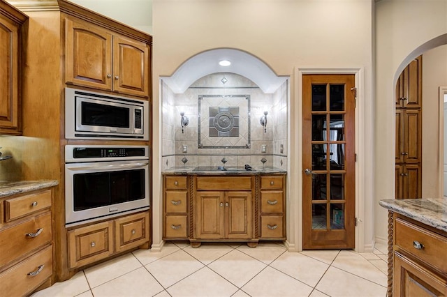 kitchen with light stone countertops, sink, decorative backsplash, light tile patterned floors, and appliances with stainless steel finishes