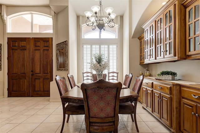 tiled dining area with plenty of natural light, a high ceiling, and an inviting chandelier