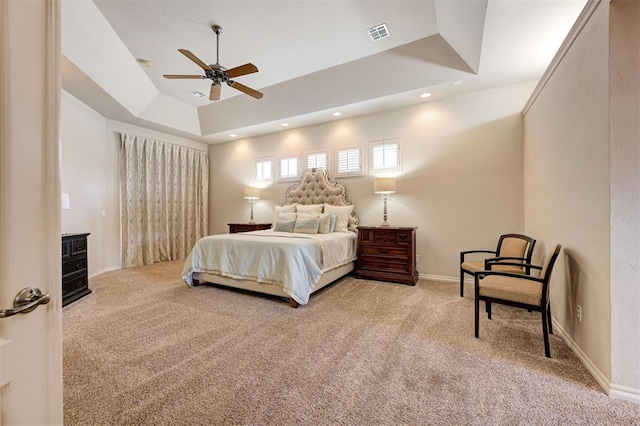 carpeted bedroom with a tray ceiling and ceiling fan