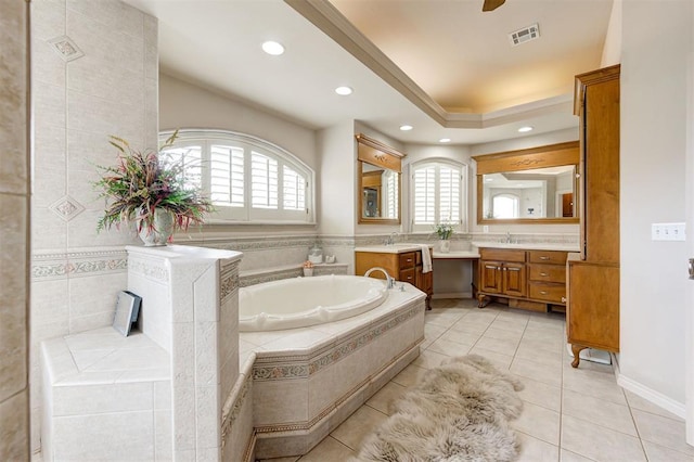 bathroom with tile patterned floors, vanity, a relaxing tiled tub, and tile walls