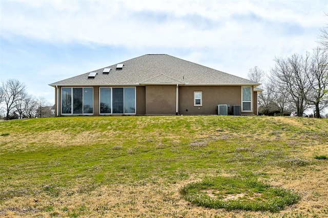 rear view of property featuring a lawn, a sunroom, and central air condition unit