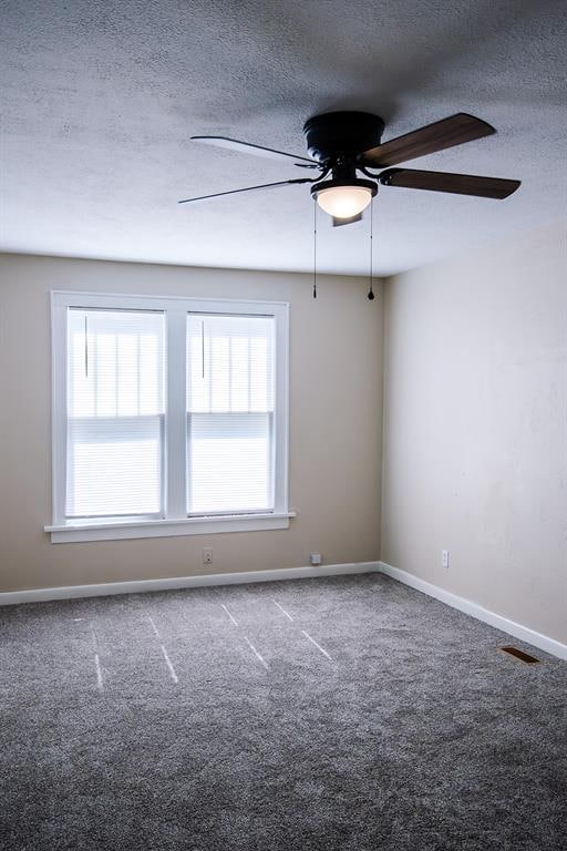 carpeted spare room featuring ceiling fan and a textured ceiling