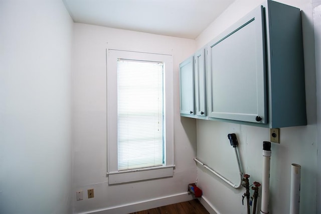 laundry area featuring electric dryer hookup, dark hardwood / wood-style flooring, and cabinets