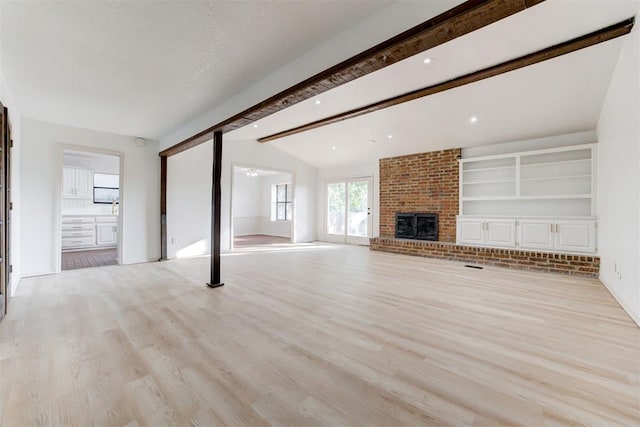 unfurnished living room with lofted ceiling with beams, light hardwood / wood-style floors, and a fireplace