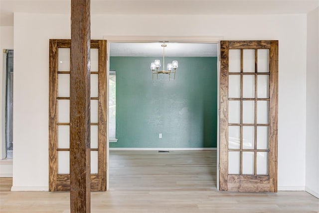 unfurnished dining area featuring light hardwood / wood-style flooring and a notable chandelier