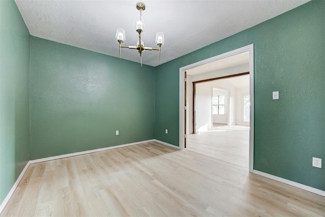 empty room with an inviting chandelier and light hardwood / wood-style flooring