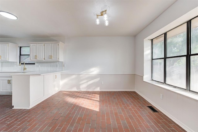 900 Woodbury Dr, Edmond, OK 73034 - kitchen with light countertops, brick floors, and white cabinetry