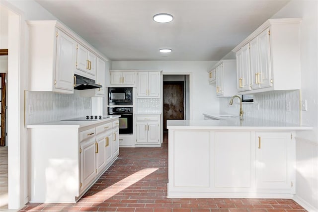 900 Woodbury Dr, Edmond, OK 73034 - kitchen with black appliances, under cabinet range hood, brick flooring, a peninsula, and light countertops