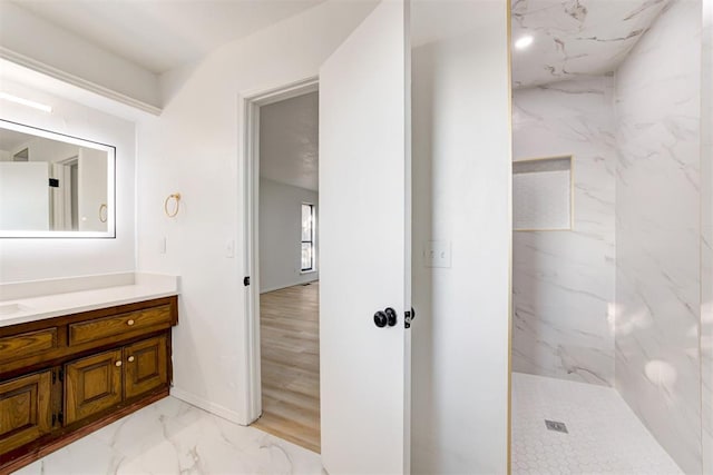 bathroom with hardwood / wood-style flooring, vanity, and tiled shower