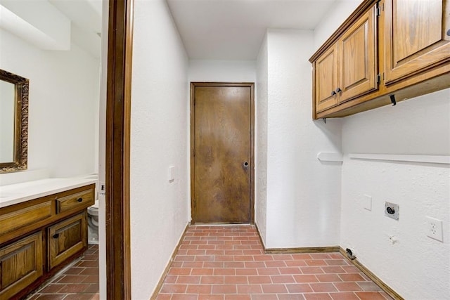 clothes washing area featuring electric dryer hookup and cabinets