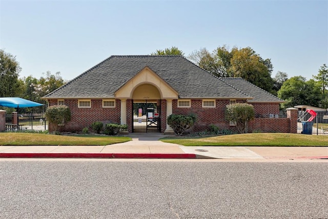 900 Woodbury Dr, Edmond, OK 73034 - english style home featuring brick siding, a gate, and roof with shingles