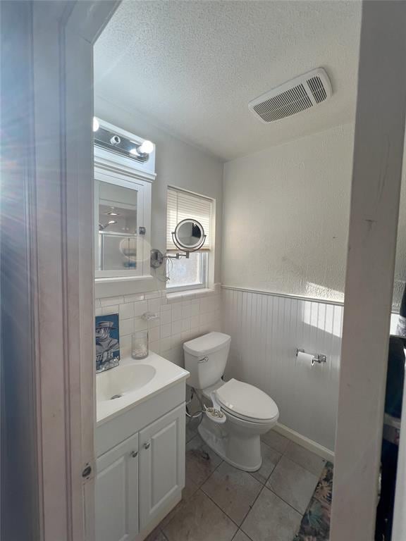 bathroom with tile patterned flooring, vanity, a textured ceiling, and toilet