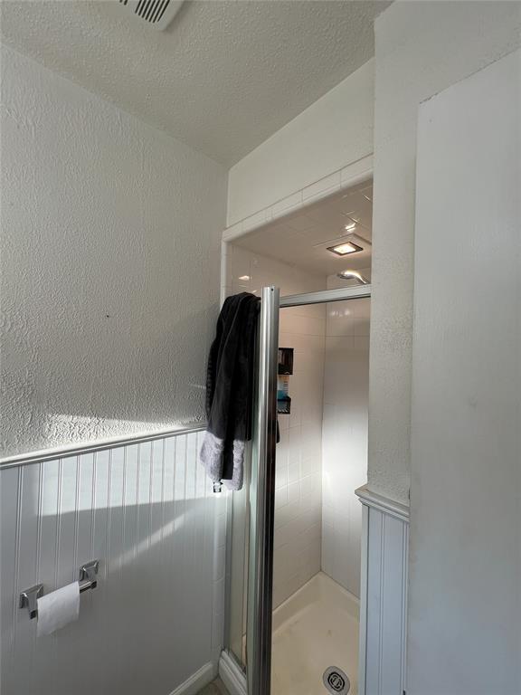 bathroom with a shower with shower door and a textured ceiling