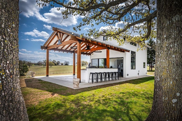 exterior space with an outdoor bar, a patio area, and a lawn