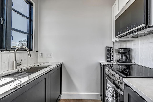 kitchen featuring light stone countertops, decorative backsplash, white cabinets, and stainless steel appliances