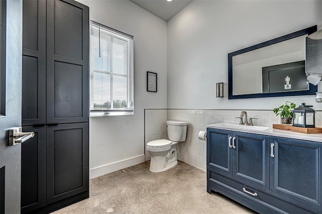 bathroom with vanity, toilet, and tile walls