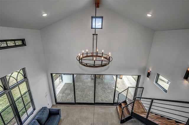 stairway with a chandelier, high vaulted ceiling, a wealth of natural light, and beamed ceiling