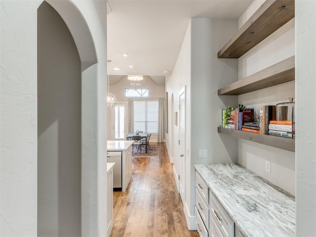 bar featuring a chandelier, light stone countertops, and light hardwood / wood-style flooring