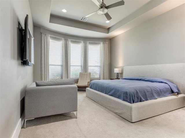 carpeted bedroom featuring a tray ceiling and ceiling fan