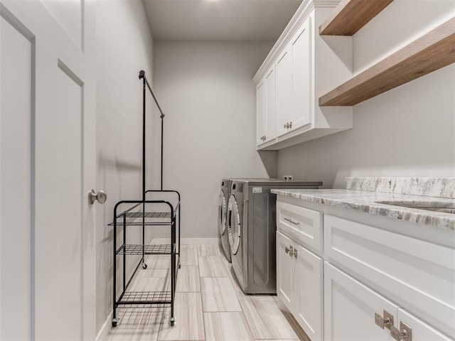 clothes washing area with cabinets and separate washer and dryer