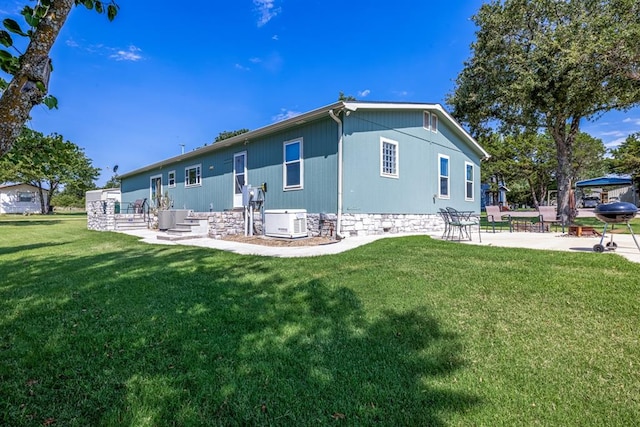 rear view of house with cooling unit, a patio area, and a yard