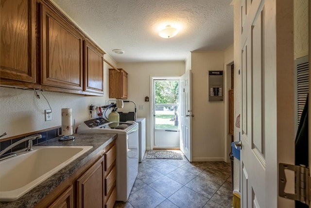 washroom with cabinets, sink, washer and dryer, light tile patterned floors, and a textured ceiling