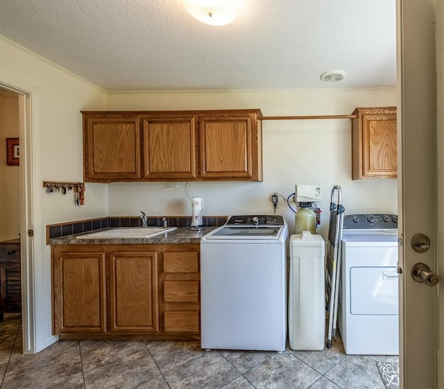 washroom with cabinets, a textured ceiling, washer and dryer, and sink