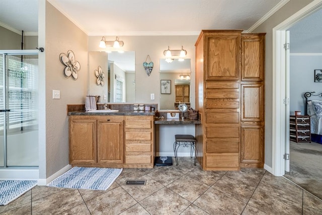 bathroom featuring vanity, tile patterned floors, a shower with shower door, and crown molding