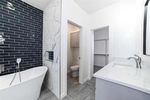 bathroom featuring a washtub, vanity, and toilet