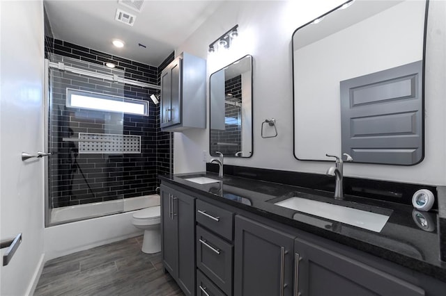 full bathroom with hardwood / wood-style floors, vanity, enclosed tub / shower combo, and toilet