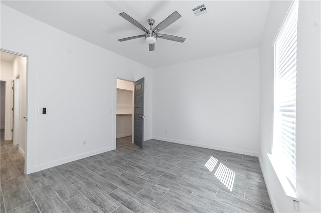 unfurnished bedroom with a closet, a spacious closet, ceiling fan, and light hardwood / wood-style floors