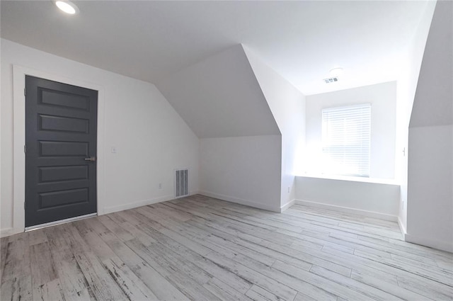 bonus room with light wood-type flooring and vaulted ceiling