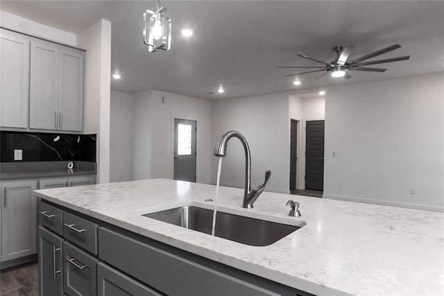 kitchen with light stone countertops, pendant lighting, gray cabinets, and sink