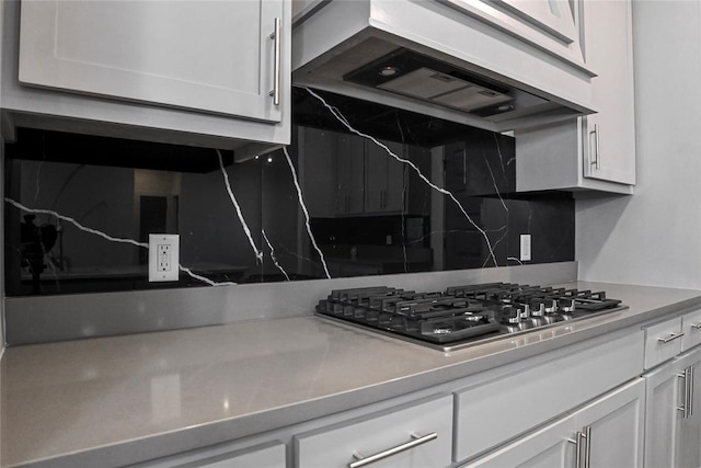 kitchen with stainless steel gas stovetop, white cabinetry, and range hood