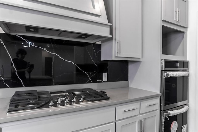 kitchen featuring white cabinets, stainless steel appliances, and exhaust hood